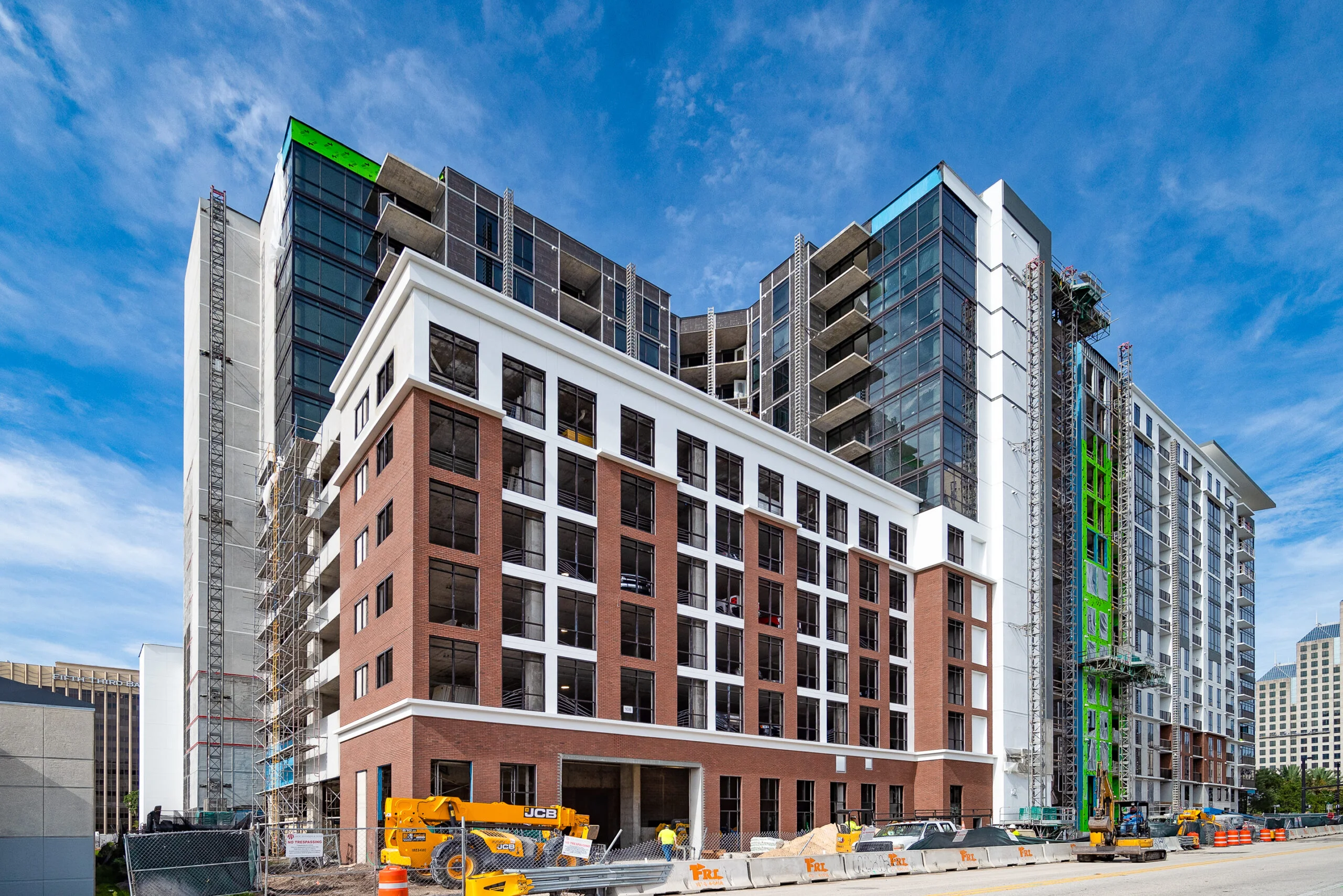 A multi-story building under construction This is an image of a multi-story building under construction, with exposed scaffolding, and a mix of completed brick facade sections and unfinished exterior portions.